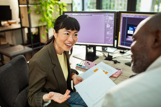 Coworkers discussing data and reports at modern office desk