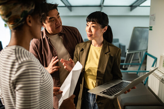 Coworkers discussing project with laptop in modern office