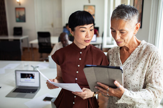 Two businesswomen reviewing data on tablet in modern office