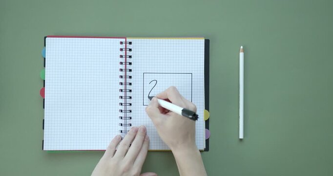Hand drawing a black rectangle on a grid notebook with a felt tip marker