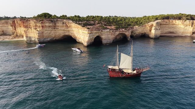 Pirate ship tourist boat sailing near benagil sea cave coastline