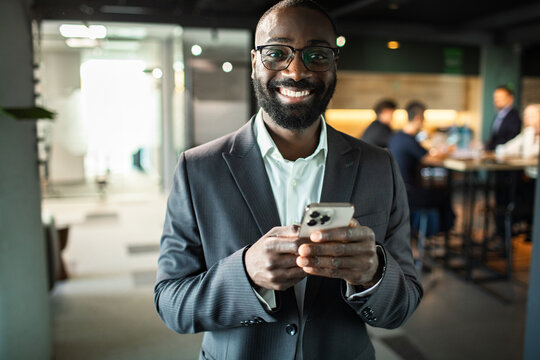 Confident businessman using smartphone in modern office