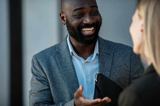 Smiling businessman talking with colleague outside office