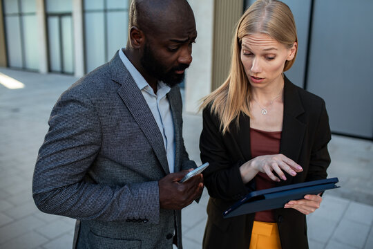 Two business colleagues reviewing tablet outside office