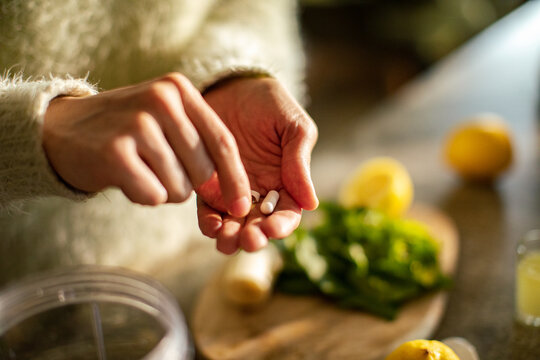 Person taking vitamin supplements in a home kitchen