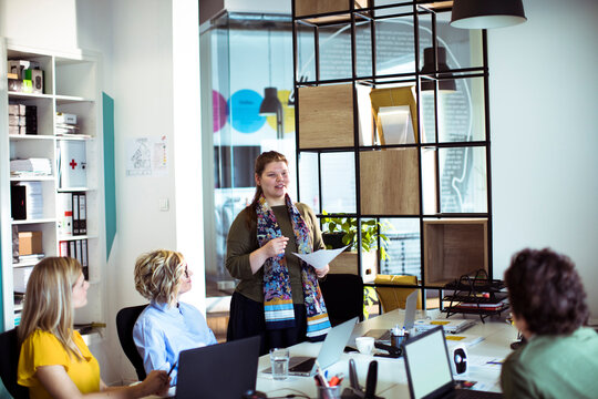 Businesswoman leading presentation to team in modern office