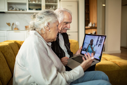Senior couple consulting doctor via laptop at home