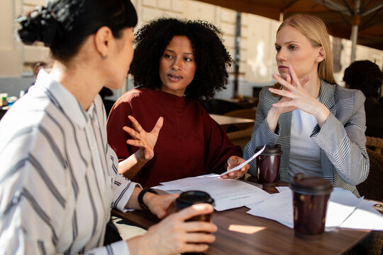 Three businesswomen discussing project at outdoor cafe
