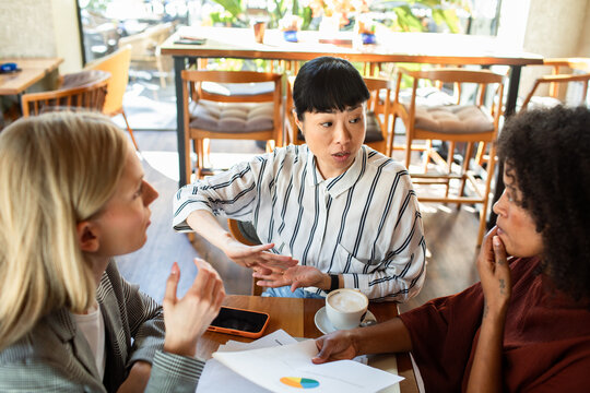 Three colleagues discussing business strategy in a cafe