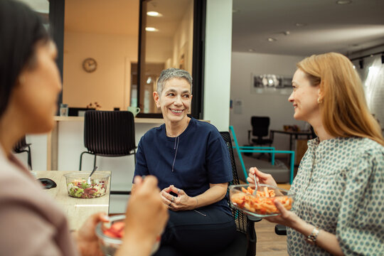 Women coworkers sharing healthy lunch break in modern office