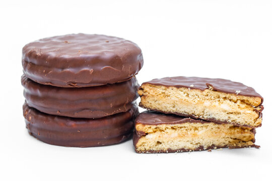 Chocolate coated biscuits with creamy filling, arranged as a stack with sliced ​​pieces showing the soft cream center, isolated on a white background
