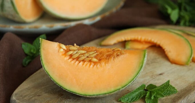 Woman taking piece of Cantaloupe melon from wooden table, closeup