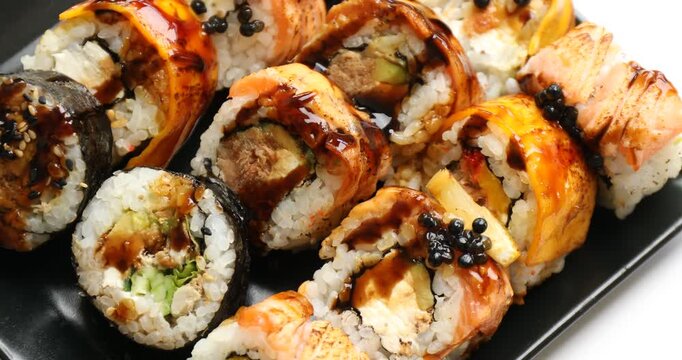 Plate with tasty sushi rolls spinning on grey table top view