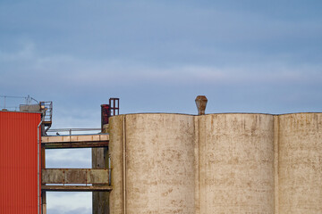 Industrial storage silos and red building under cloudy sky in daylight © Holger