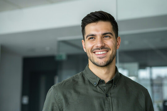 Portrait of handsome smiling young businessman in green shirt in modern office.