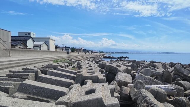 Coastal view of Kurobe Port featuring concrete tetrapods and a strong breakwater under a blue sky in Toyama, Japan. Ideal for disaster prevention and infrastructure concepts.