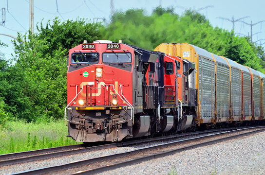 A trio of locomotives, led by a Canadian National Railway unit, provide front-end power for a westbound auto rack train on Burlington Northern Santa Fe tracks in northeastern Illinois.