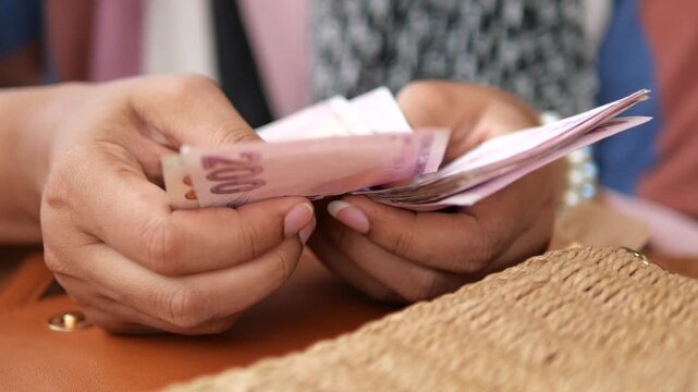 Woman hands counting turkish lira banknotes over brown leather bag in slow motion dynamic footage