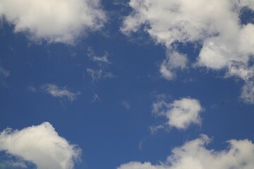Fototapeta premium Bright blue sky with scattered white fluffy clouds during daytime nature scenery