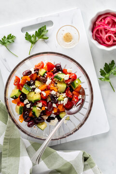 A fresh Greek Salad on a white cutting board with colourful ingredients.
