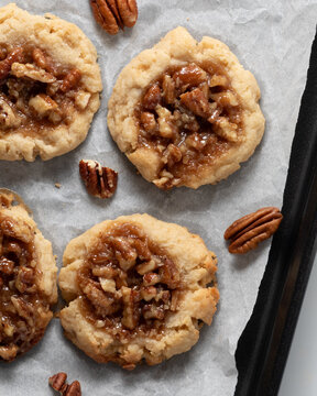 Above view of homemade pecan pie cookies on a parchment lined baking sheet.