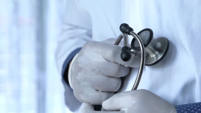 Professional doctor holding stethoscope close up footage of medical specialist in white lab coat and protective gloves
