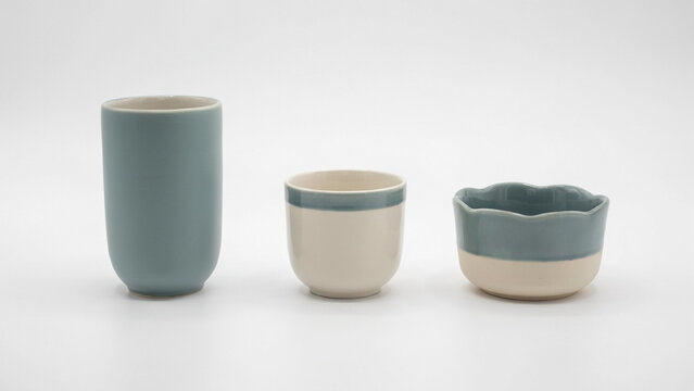 Three ceramic vessels with blue and white glazed finishes on a plain white background surface