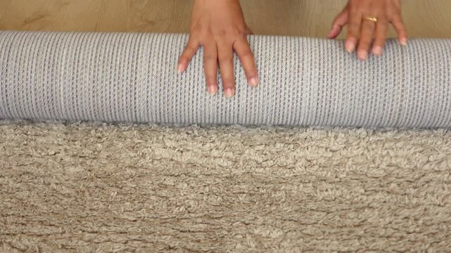 Rolling up carpet by hands on floor close up detail
