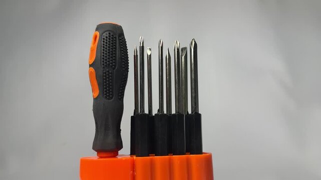 Interchangeable screwdriver bit set with orange handle in holder
