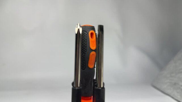 Interchangeable screwdriver bit set with orange handle in holder