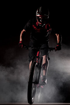 Male bicyclist riding dirty downhill mountain bike. Studio shot with smoke in the air