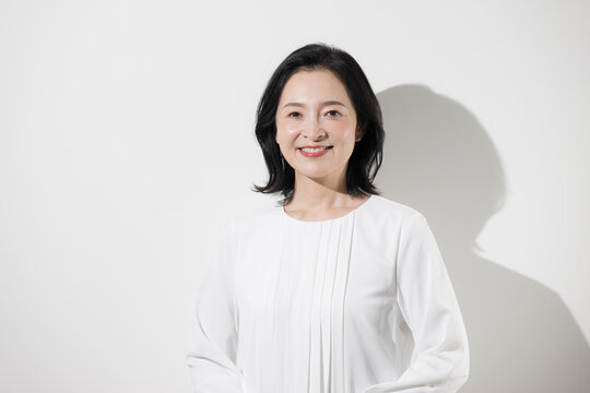 [白背景]笑顔で正面を向く日本人ミドル女性、健康的で信頼感と安心感のある50代女性のポートレート