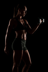 Fototapeta premium Woman Lifting Dumbbells Demonstrating Strength and Fitness in a Dark Studio Setting