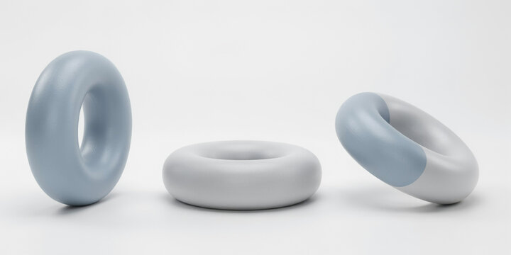 Three smooth torus shaped sculptures in soft blue and white colors on white background