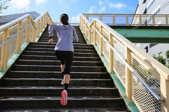 Fitness asian woman running upstairs of the overpass in Japan