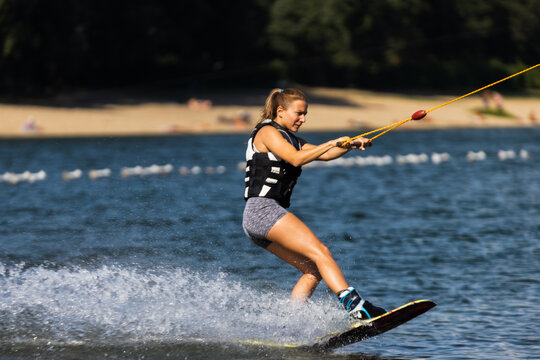 Female wakeboarder wakesurfing. Girl riding waterski cabel. Holding tow rope. Summer activities in the lake.