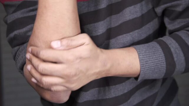 Man holding elbow in pain, close-up of painful joint, medical concept