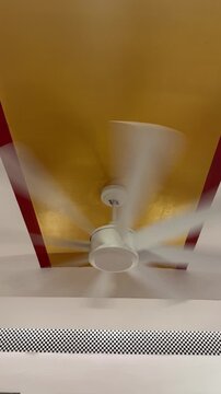 Ceiling fan spinning fast mounted on yellow painted ceiling