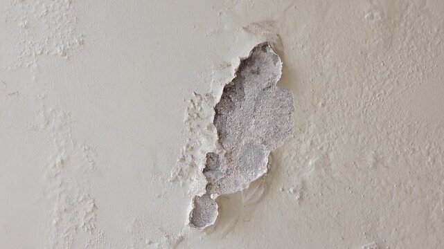Damaged wall surface with peeling paint and exposed concrete
