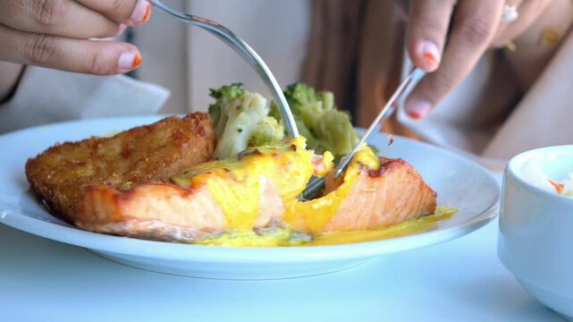 Close up of person eating salmon dish with broccoli and potato hash