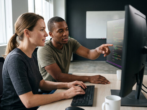 Two developers reviewing code together at a shared monitor