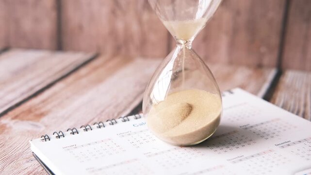 Hourglass running out of sand on calendar marking time and deadlines