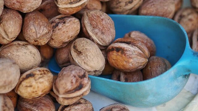 A blue scoop filled with walnuts sits prominently on a market display