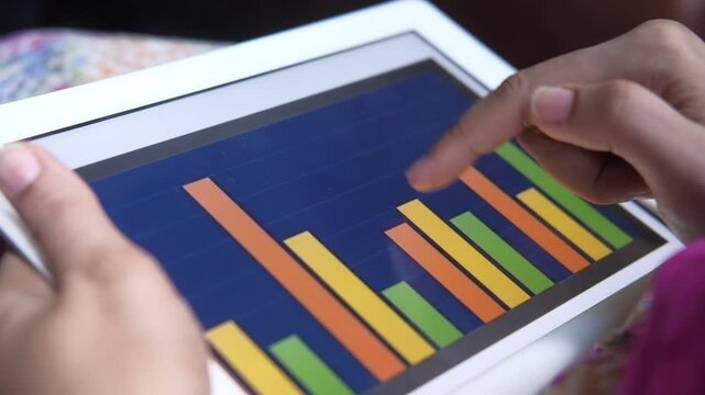 Woman hands using digital tablet for analyzing business growth bar charts in close up footage