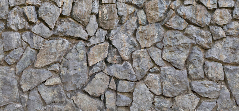 Grey stone masonry wall made of irregular cut rocks with rock wall grey stones stone texture wall construction building material stone background rough surface exterior wall stacked rocks