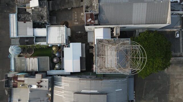 Top-Down Aerial Footage of Water Tower Infrastructure with a Circular Steel and Metal Framework Structure on a Building Roof. The Industrial Utility Structure Reveals Geometric Patterns from Above.