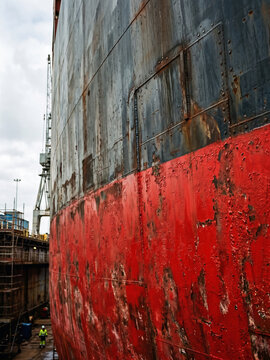 Weathered cargo ship hull undergoing repairs in dry dock
