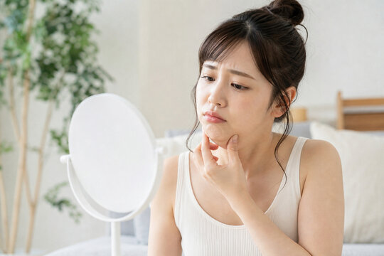 鏡を見ながら二重あごを気にする若い女性