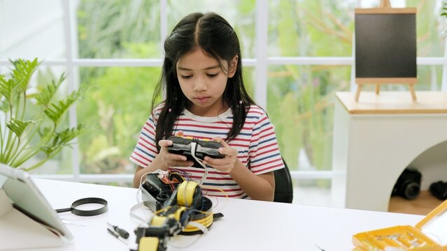 Intelligent Young Student Using Handheld Remote Controller to Test Motorized Robotic Arm Model on Desk at Home 4K