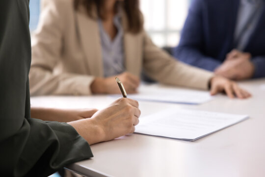 Close up businesswoman signing agreement on paper document at meeting table closing business deal with partners completing signature on employment contract affirming insurance or investment paperwork
